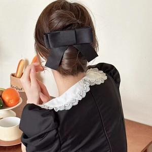 Détail d'une grande pince à cheveux avec nœud en satin noir et longs rubans au style français