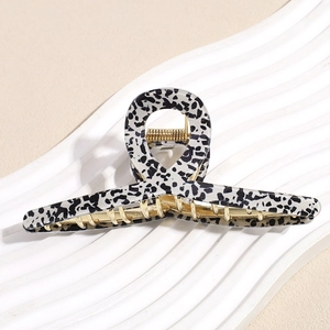 Detail of large leopard print hair claw clip with golden metal spring on white stand
