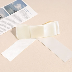 Gros plan détaillé d'un nœud en satin crème avec de longs rubans et une texture soyeuse