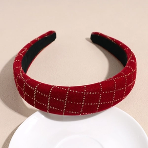 Détail du serre-tête en velours rouge avec texture quadrillée dorée sur plat