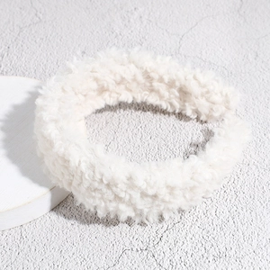 Detailed view of plush white faux lamb wool headband texture on a minimalist stone surface