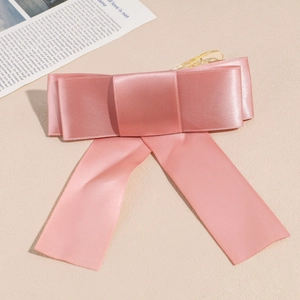 Détail d'une pince à cheveux à nœud en satin rose avec rubans sur fond beige élégant
