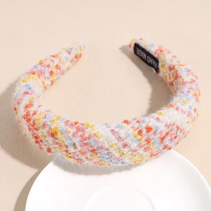 Detail of colorful tweed wide headband with a handmade label on woven plush fabric