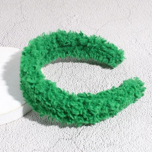 Detailed view of bright green faux shearling headband on a textured stone surface