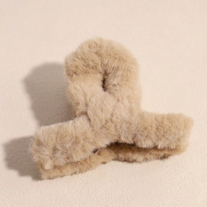 Détail de la texture pelucheuse et du design de la pince à cheveux en fausse fourrure beige