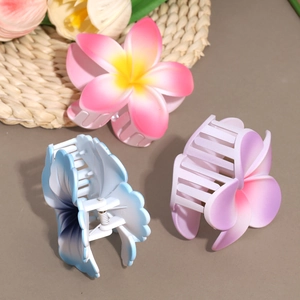 Three gradient floral hair claw clips with plumeria design on a warm aesthetic background