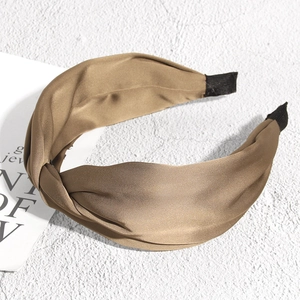 Détail d'un serre-tête en satin marron torsadé avec texture douce et embouts de protection