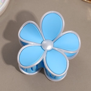 Vue détaillée d'une pince à cheveux fleur bleue mate avec des bords blanc nacré