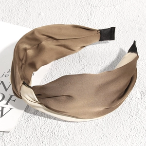Détail d'un serre-tête en satin rayé marron et beige avec un design de nœud torsadé