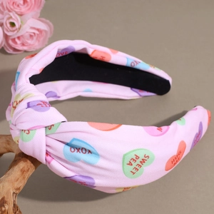 Dettaglio fascia rosa a nodo con stampe a cuore e scritte XOXO e HUG ME