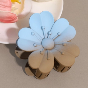 Detail view of flower hair claw with blue gradient matte finish on a minimalist surface