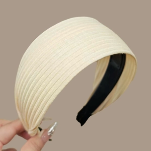 Detail of a beige ribbed knit wide headband showing soft fabric texture and inner black lining
