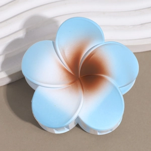 Detail view of a matte gradient plumeria hair claw clip with blue and brown petals