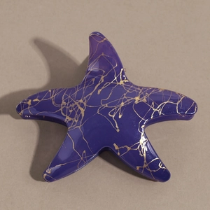 Détail d'une pince à cheveux étoile de mer violette avec motif marbré doré de style