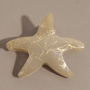 Détail macro d'une pince à cheveux étoile de mer avec textures dorées et fini résine