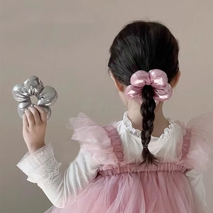 Detail eines rosa Haar-Scrunchies mit Metallic-Finish am Pferdeschwanz getragen