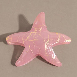 Vue détaillée de la pince à cheveux étoile de mer rose avec marbrures dorées