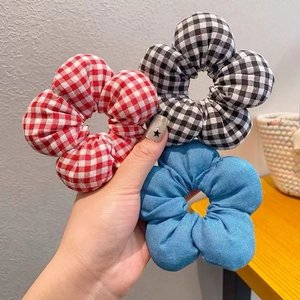 Detailansicht von drei großen Blumen-Haargummis in Rot-Karo, Schwarz-Karo und blauem Denim