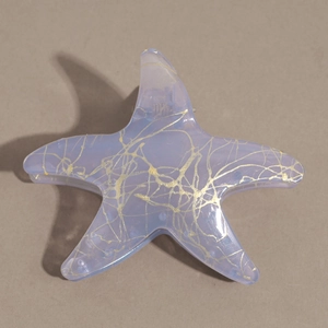 Détail d'une pince à cheveux étoile de mer avec dégradé violet et paillettes d'or