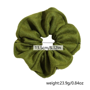 Detail view of a dark green scrunchie showing 13.5cm diameter and 23.9g weight