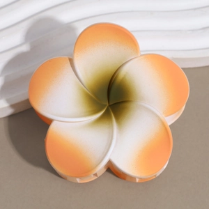 Detailed macro view of matte finish plumeria hair claw clip with gradient orange center