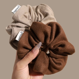 Knitted fabric scrunchies in caramel and beige colors with a happiness woven label