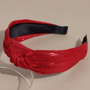Détail du serre-tête rouge pailleté avec nœud et texture côtelée sur un support