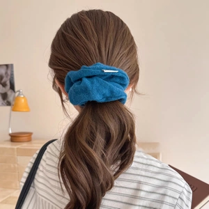 Dark blue knitted scrunchie hair tie styled on a low ponytail for an elegant winter look