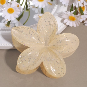 Nahaufnahme der cremefarbenen Blumen-Haarklammer mit Glitzer-Finish auf Deko-Fläche