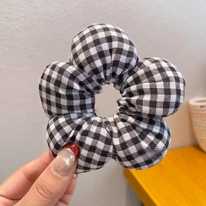 Detail eines gepufften schwarz-weißen Gingham-Blumen-Haargummis mit weichem Stoff