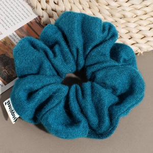 Detailed view of dark green knitted scrunchie with Happiness woven label texture