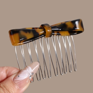 Macro view showing tortoise shell bow acetate comb with glossy metal teeth detail