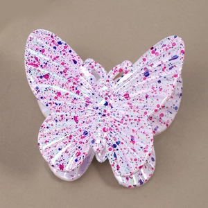 Detailed macro view of butterfly hair claw clip with colorful ink splatter on pearl finish