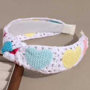 Dettaglio della fascia bianca lavorata a mano a maglia con cuori colorati e texture crochet