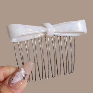 Close-up of acetic acid bow hair comb with polished metal teeth and marble texture