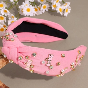 Detail of pink knotted headband featuring pearls, crystals, and gold LOVE charms