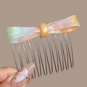 Detail of 14-tooth metal hair comb with colorful pearlescent acetate bow decoration