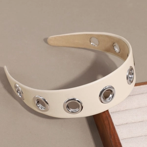 Détail d'un serre-tête en cuir PU crème avec de gros œillets métalliques argentés style punk