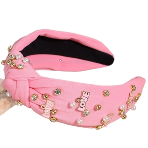 Pink knotted headband with rhinestones, pearls and LOVE letters on white background