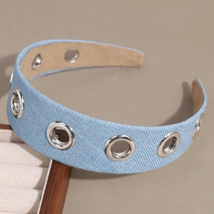 Blue denim headband with metal grommets and hollow punk rivets on a warm background
