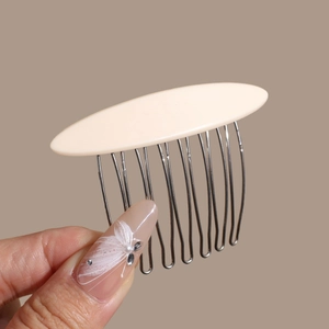 Detailed close-up of cream acetate hair comb with polished metal teeth held in hand
