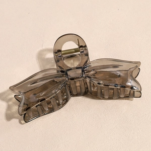 Close-up of a large smoke gray translucent bow hair claw clip with strong metal spring