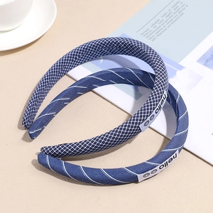 Blue plaid and striped padded headbands with hello smile tag on a beige surface