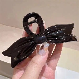 Elegant large black glossy bow hair claw clip for thick hair styling held in hand