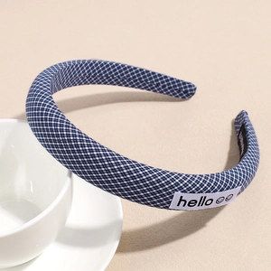 Close-up of blue gingham fabric headband with small 'hello' smiley face woven label