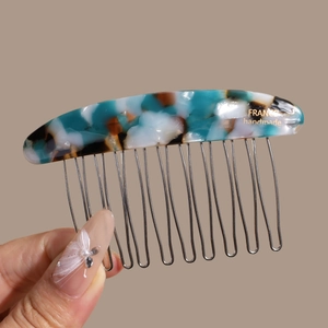 Detail of handmade acetate hair comb with marble pattern and 12 silver metal tines