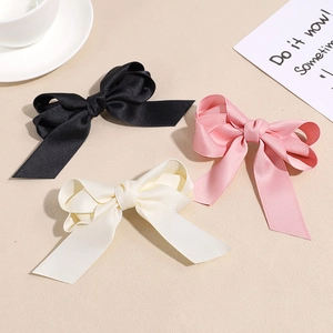 Three-piece set of satin bow hair clips in black, pink, and cream with long ribbons