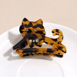 Détail de la pince à cheveux chat en écaille avec strass brillants sur assiette en céramique