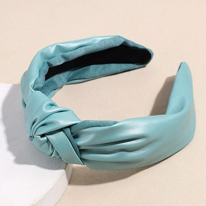 Detail view of the cyan faux leather knotted headband showing texture and velvet lining