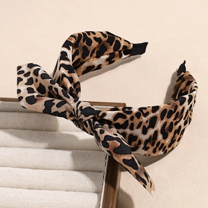 Close-up of a leopard print bow headband with non-slip teeth on a neutral display surface